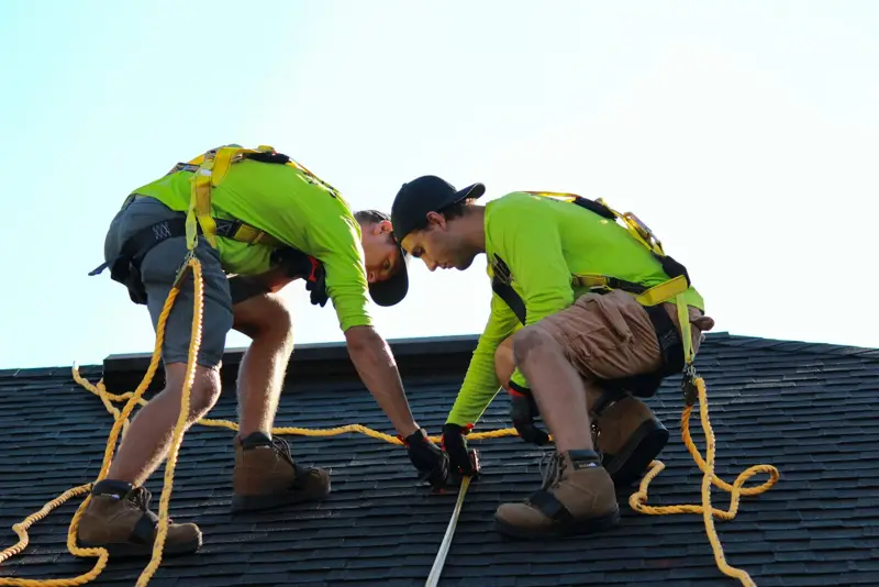 Two roofers installing new shingles